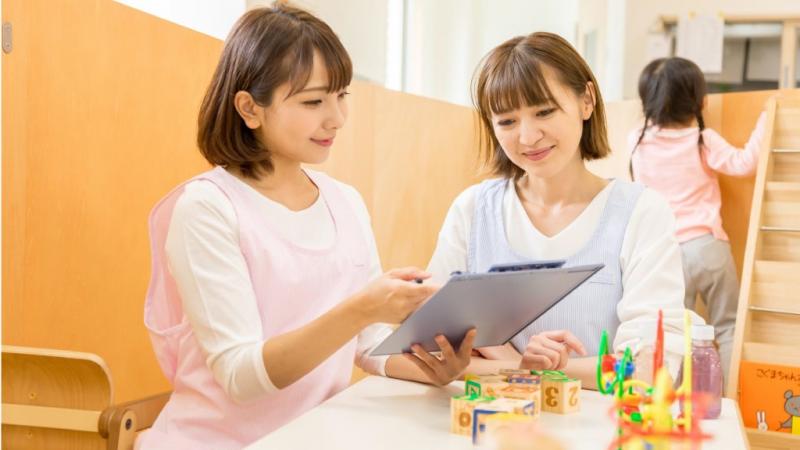 バインダーを見ながら話しをする女性保育士2人