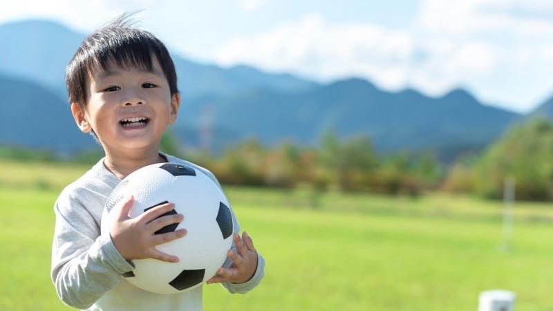 草原でサッカーボールを持っている男の子