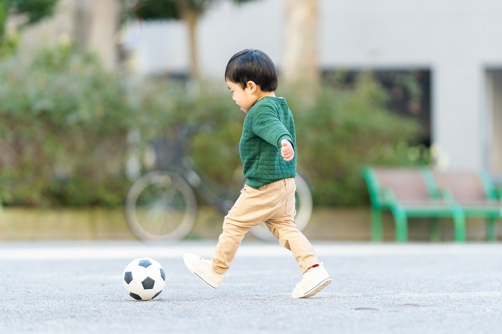 屋外でサッカーボールを蹴ってのびのびと遊ぶ男の子