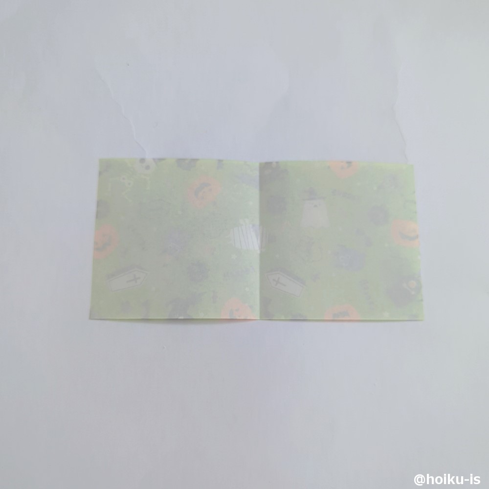 裏返して白い面を上にし、真ん中で半分に折り筋を付けます