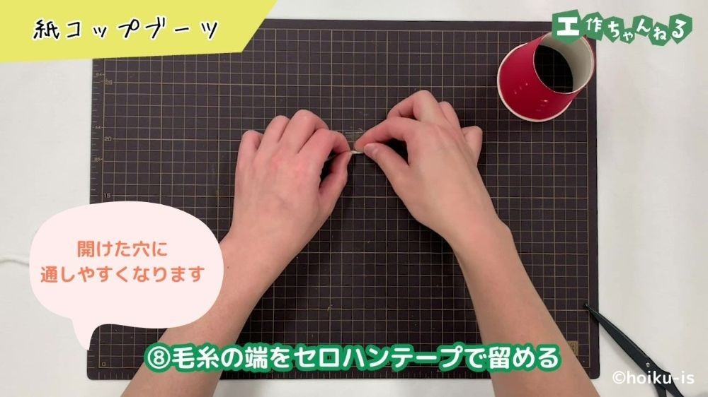 毛糸の端をセロハンテープで留めている手元
