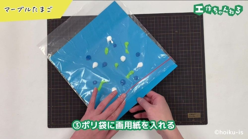 絵の具をつけた画用紙をポリ袋に入れている手元