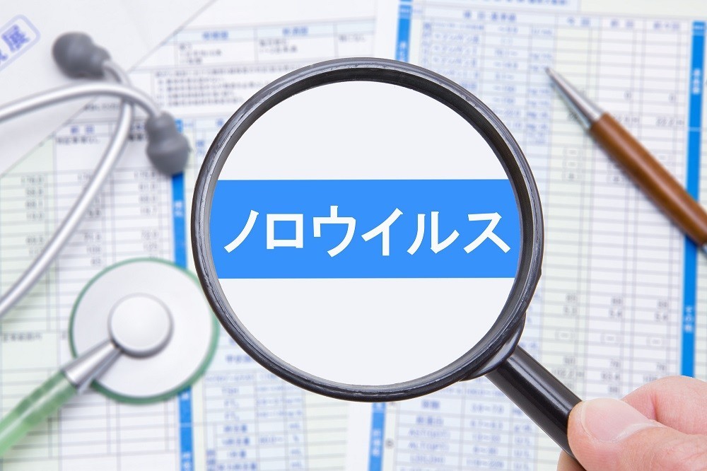 虫眼鏡で拡大された「ノロウイルス」の文字