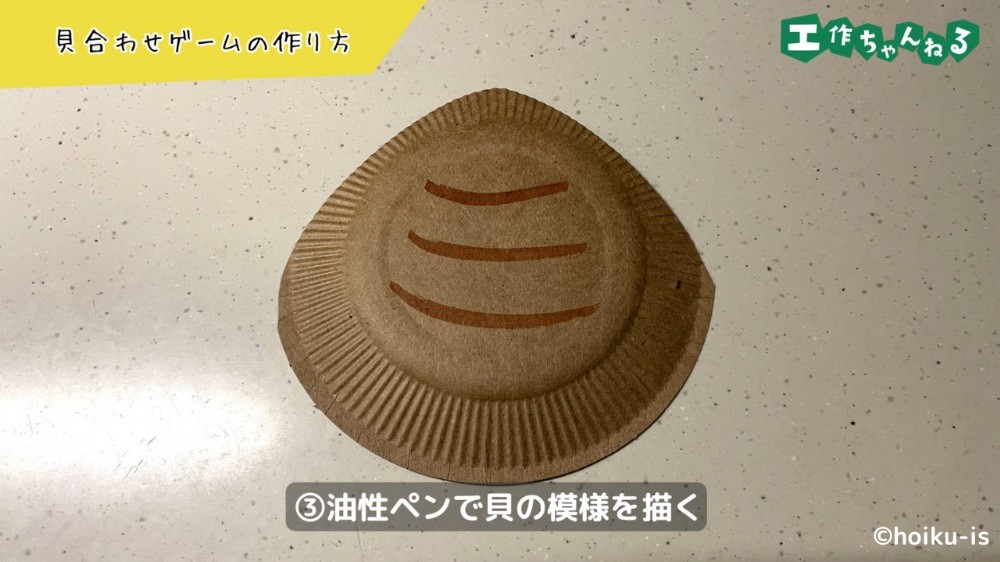 ペンで紙皿に貝の模様を描く