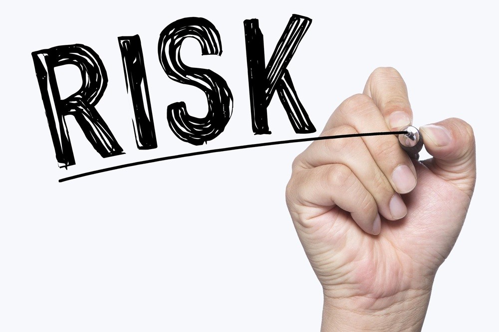 「RISK」の文字をボードに書いている手元