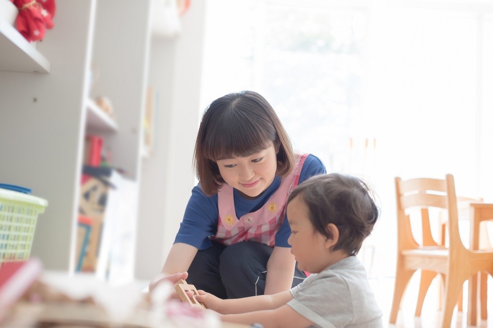 木のおもちゃで遊ぶ子どもと保育士