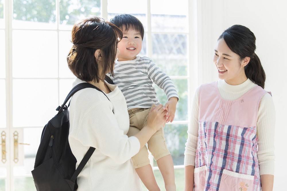 お迎えに来た保護者と話をする保育士