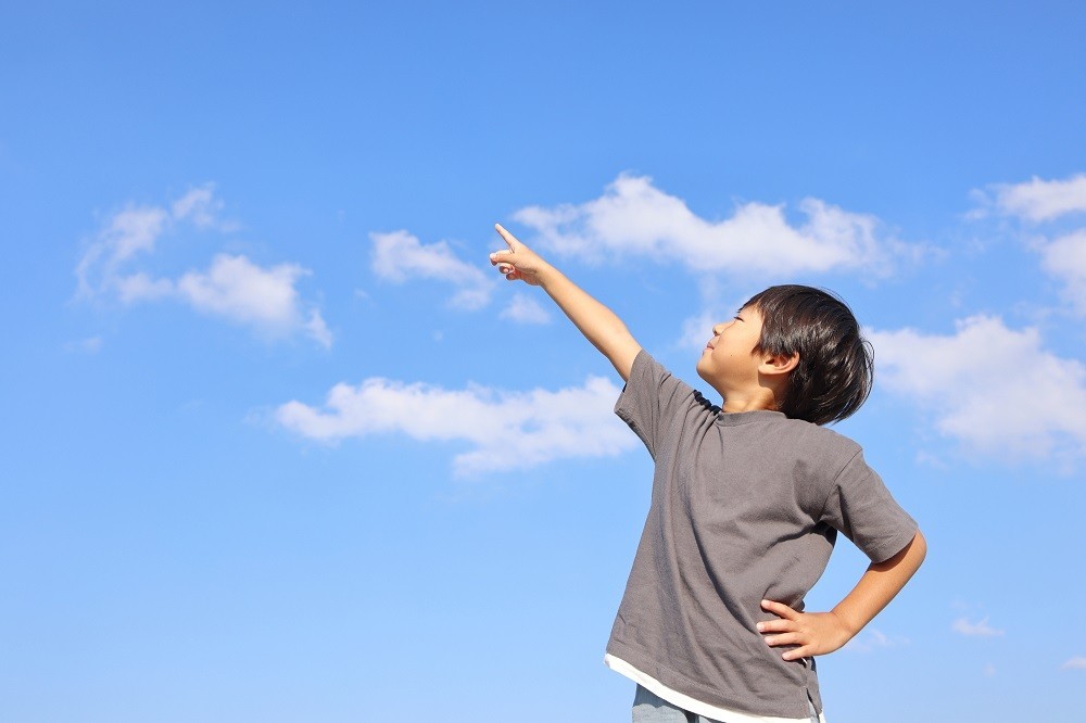 青空の方を指さしている男の子