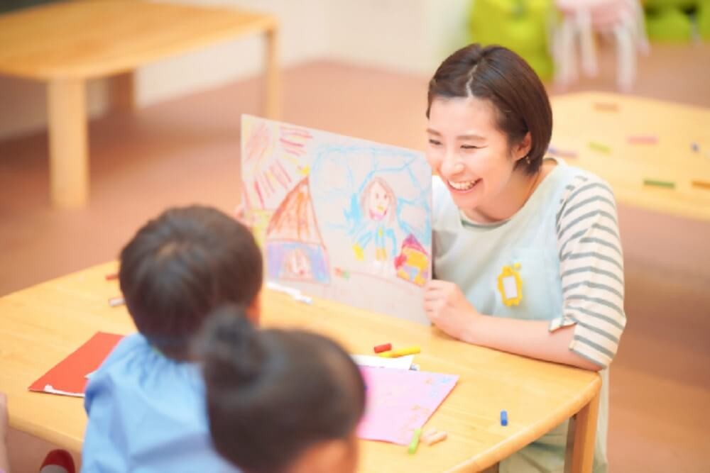 子どもに絵を見せる保育士