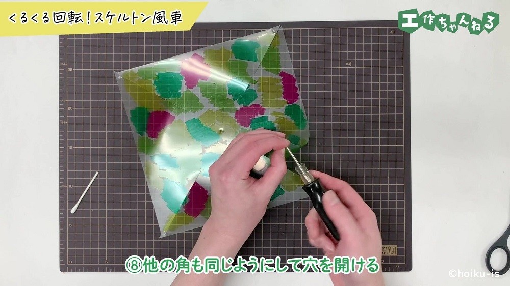 クリアファイルを折り曲げて穴を空けている手元