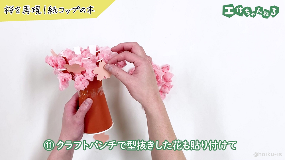 桜の花びらに型抜きした画用紙を貼り付けている様子