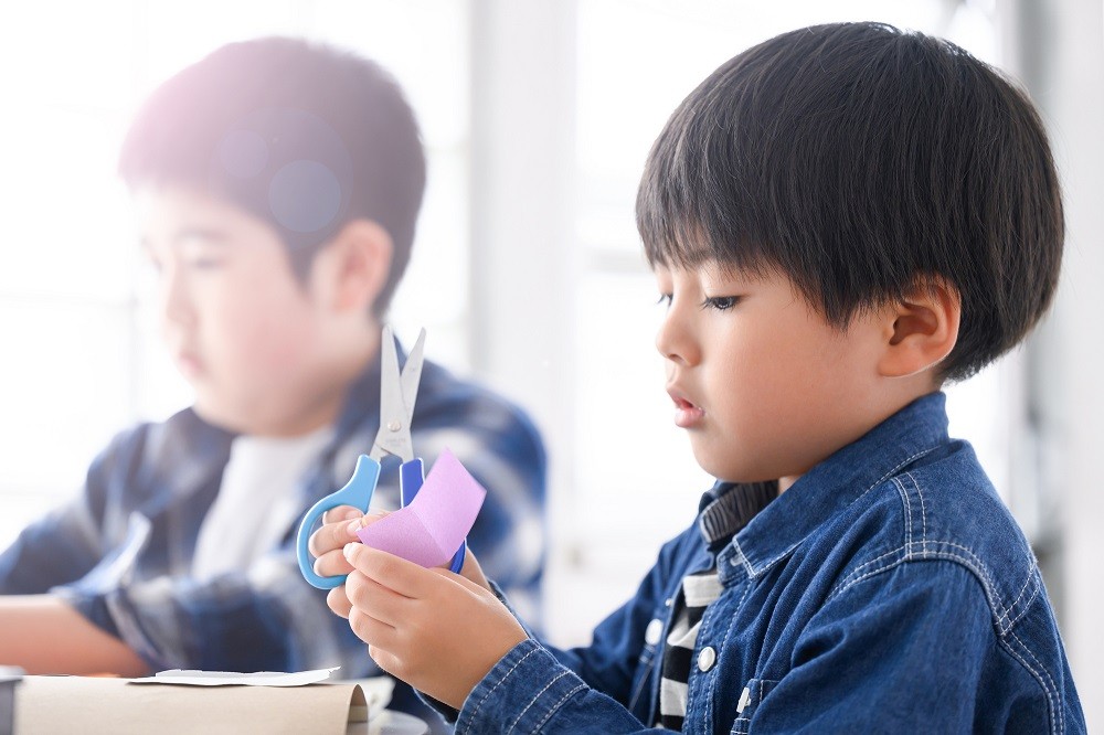 ハサミを持って工作に熱中している男の子