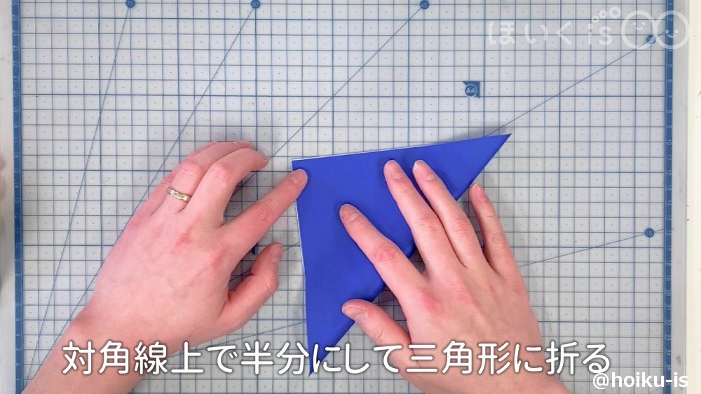 折り紙を対角線上で半分にして三角形に折っているところ