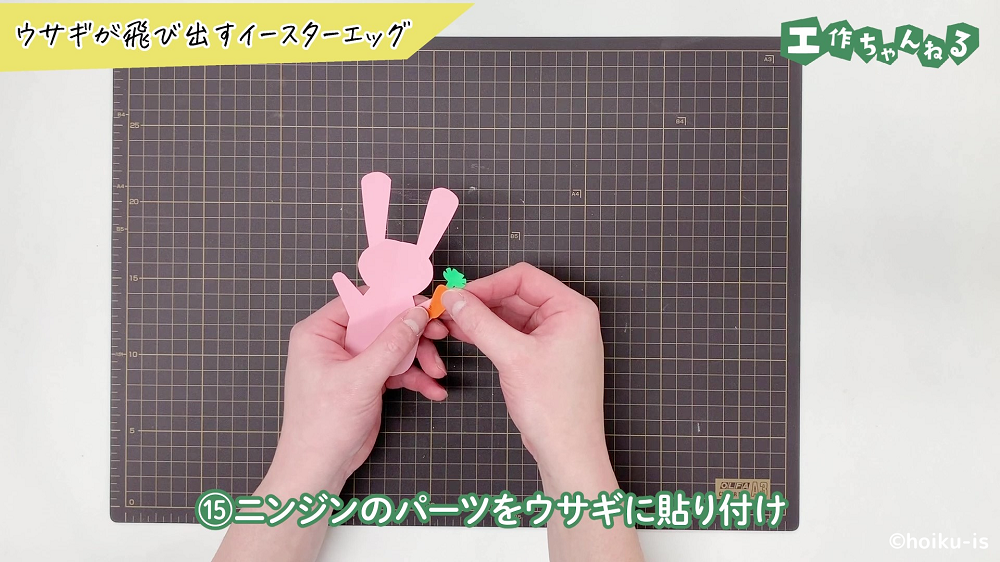 画用紙で切ったウサギにニンジンのパーツを貼り合わせている手元