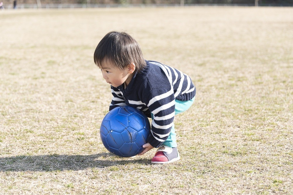 青いサッカーボールを持っている子ども