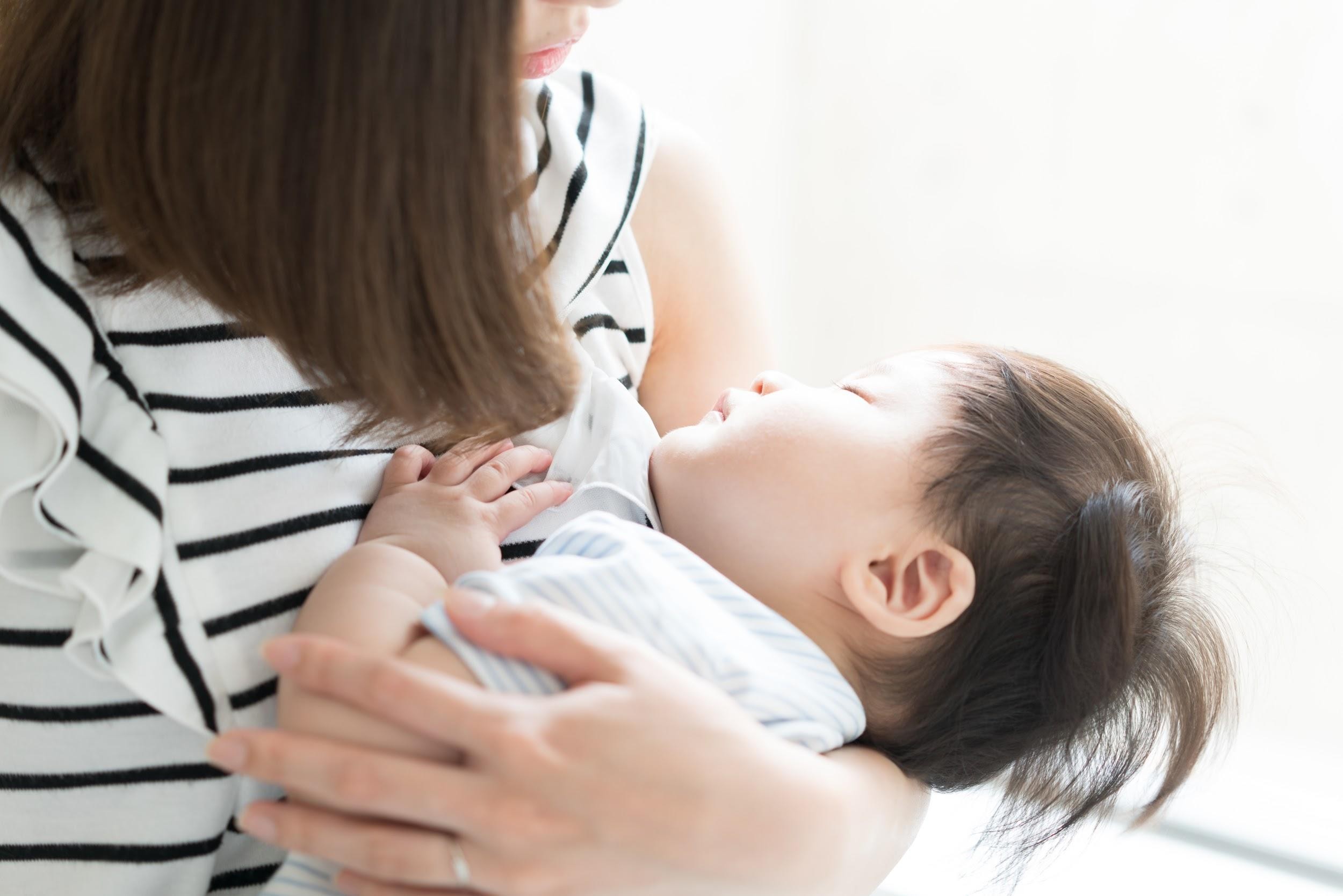 寝ている子どもを抱いている女性