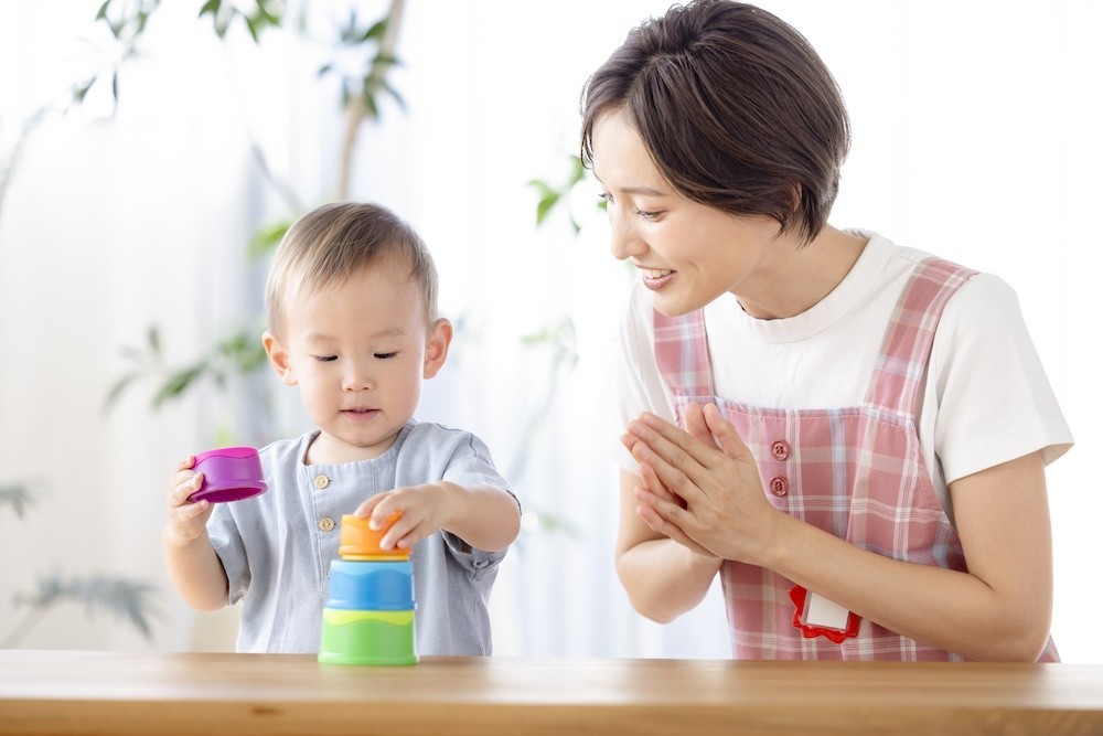 ブロックを積み重ねる子どもと見守る保育士