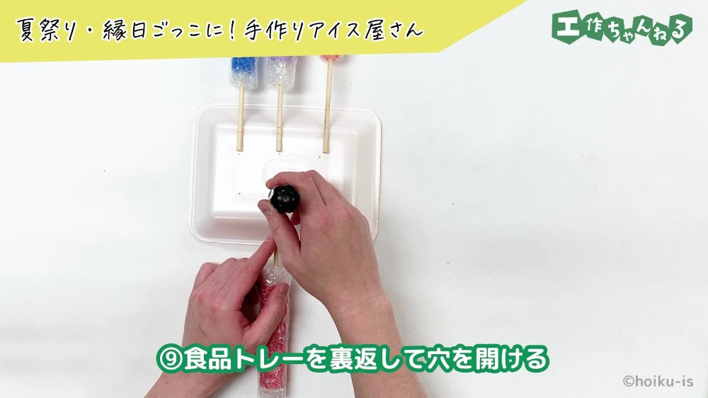キリで食品トレーに穴を開けている手元
