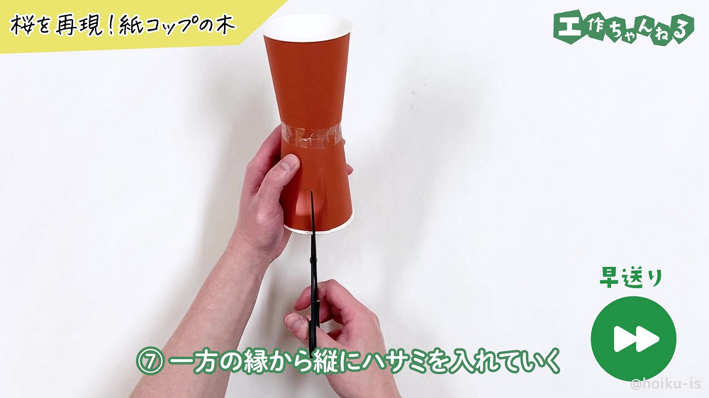 紙コップの縁に切れ込みを入れている様子