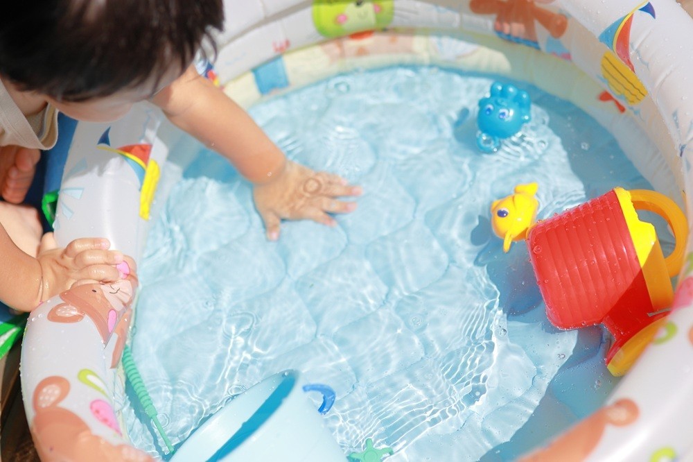 水が張られたビニールプールと子ども