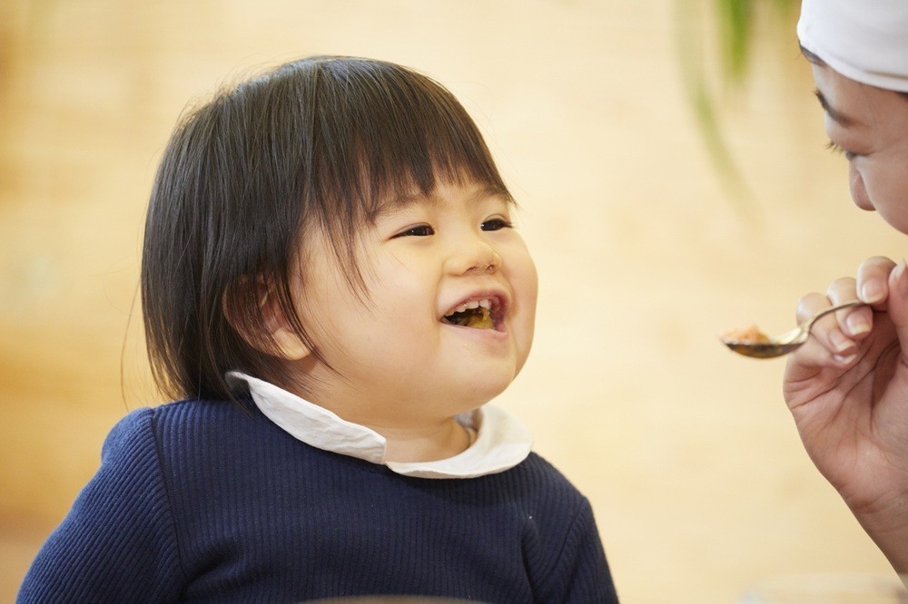 給食の介助をする保育士と園児