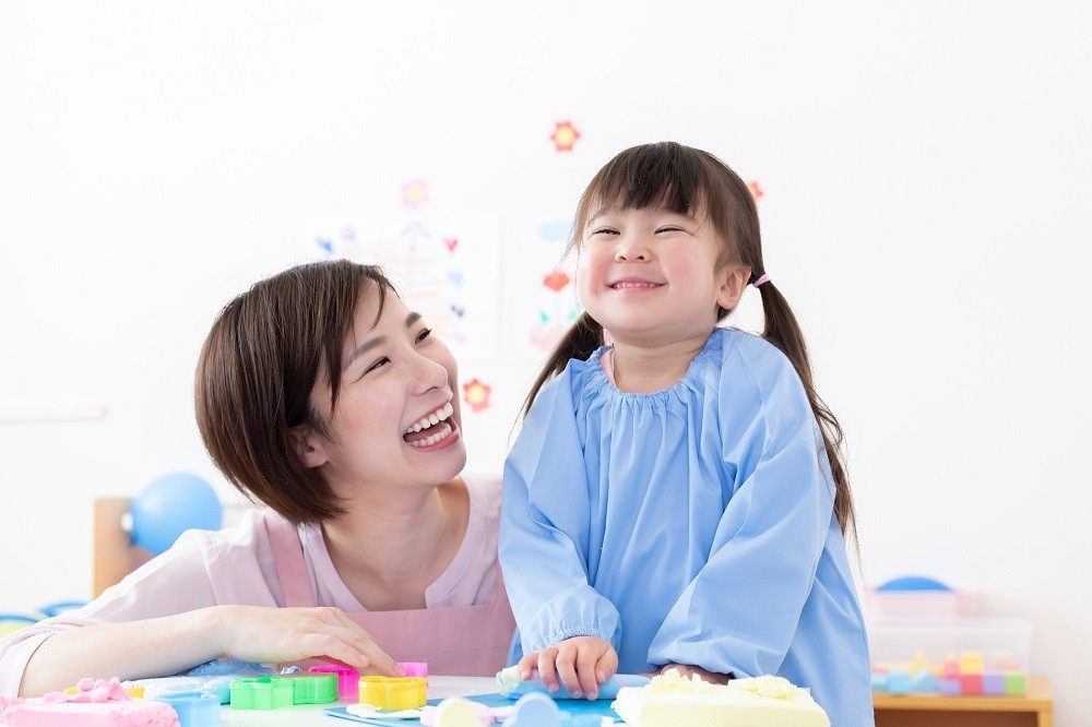 粘土遊びをする2歳児と保育士