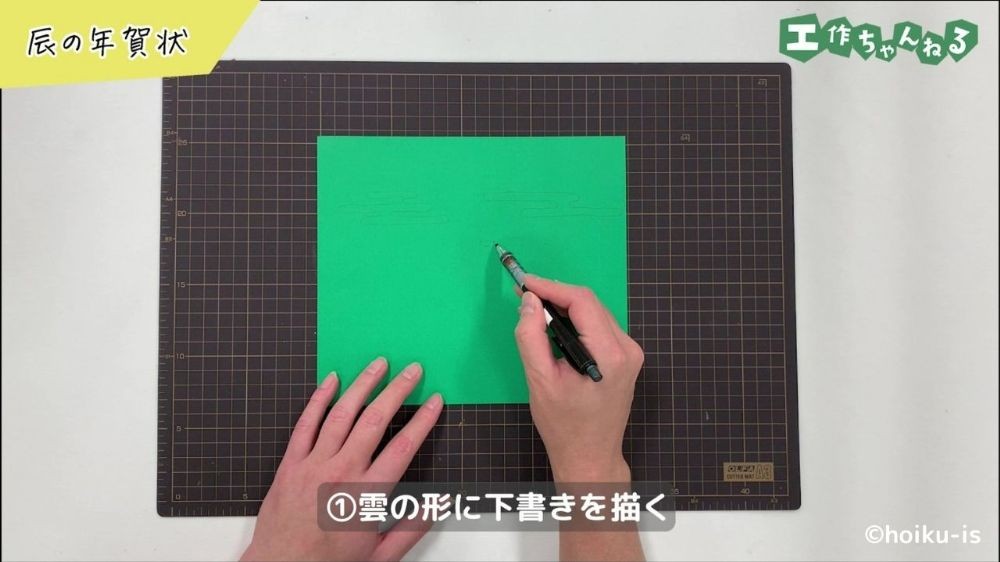 ペンで画用紙に下書きをしている手元