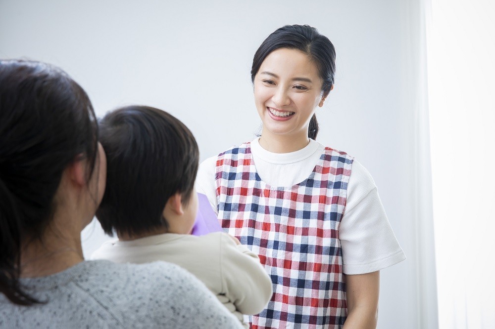 子どもを抱いた保護者と話をする保育士
