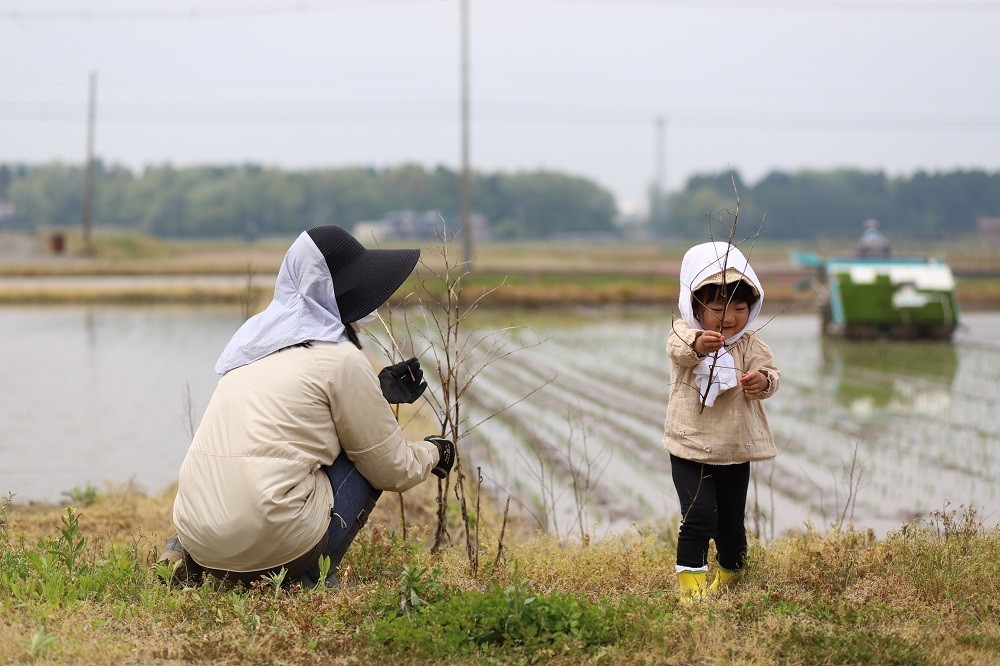 田植えをしている地域の農家と交流する子ども