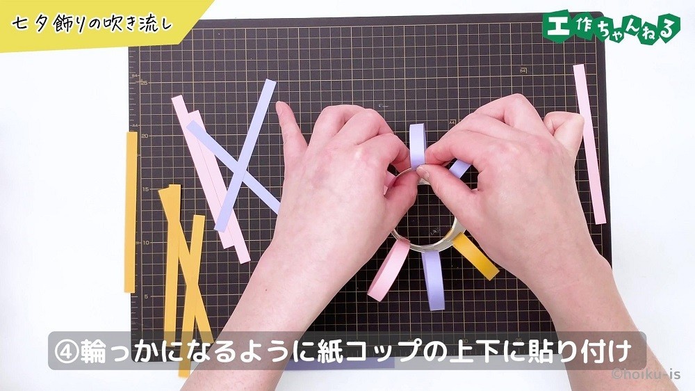 細長く切った色画用紙を紙コップに貼り付けている手元