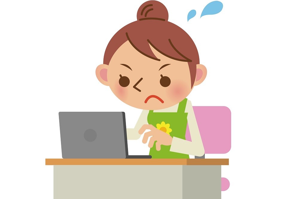 ノートパソコンに向かって焦りながら仕事をしている保育士