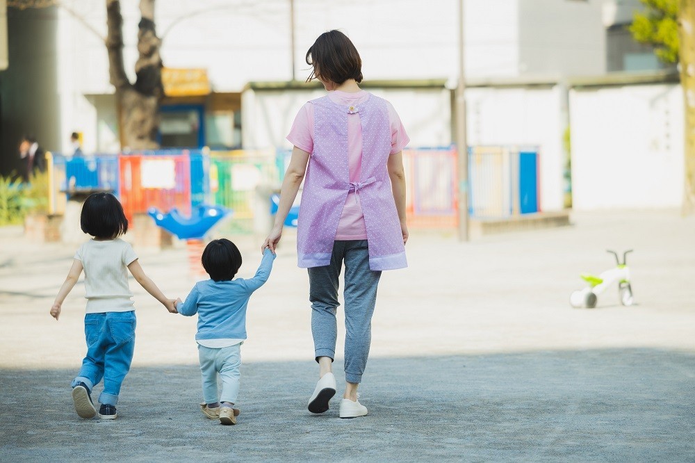 2人の子どもと手を繋いで歩く保育士