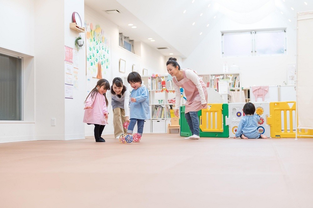 室内で保育士と遊ぶ園児たち
