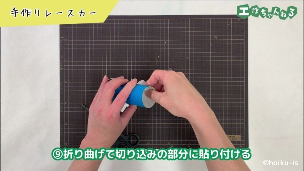 トイレットペーパーの芯に画用紙を貼り付けている手元