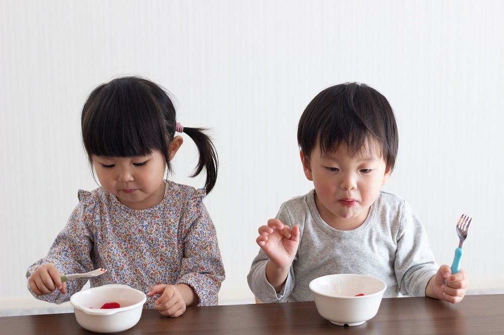 フォークを使って食べている2人の子ども
