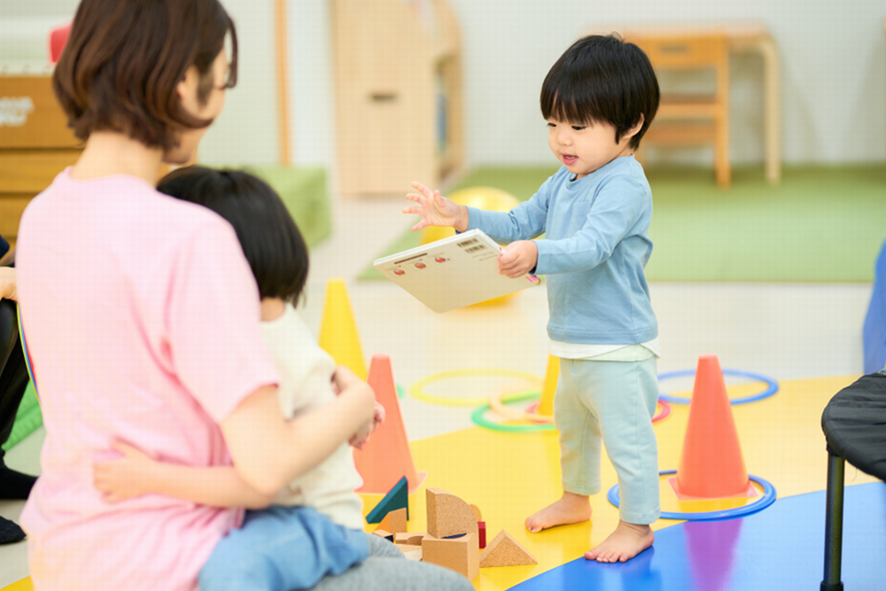 絵本を持つ子どもと保育士
