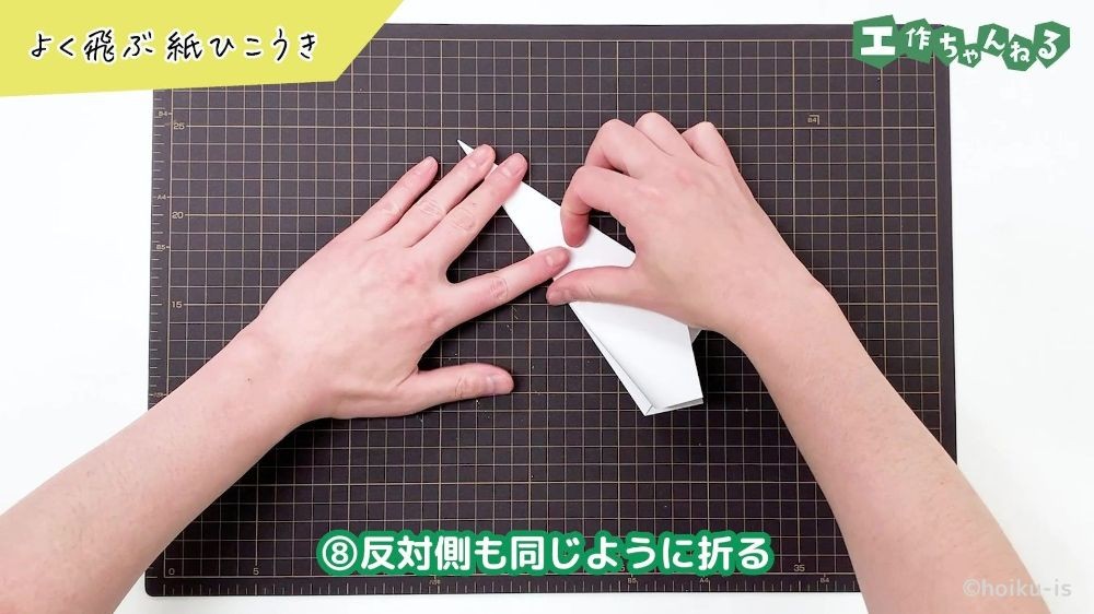 紙飛行機の羽の部分を折り返している手元