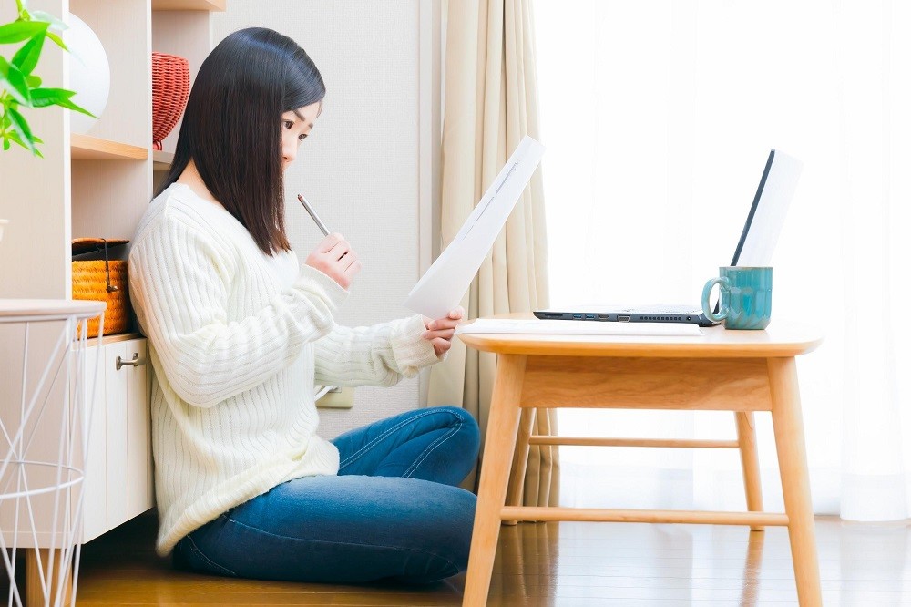 書類を手に持って考えている女性