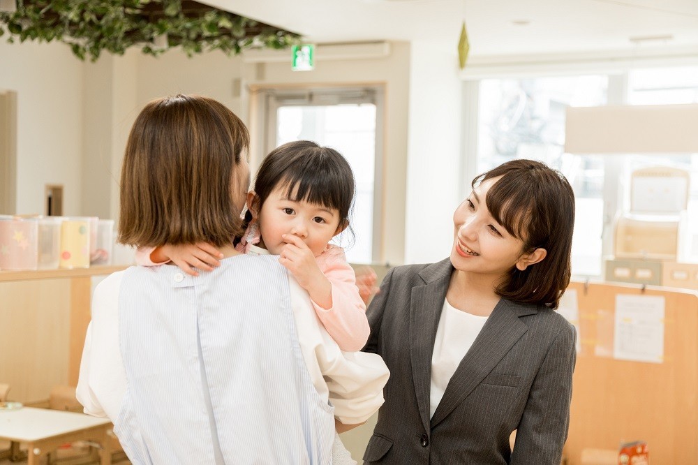 保育士と会話を交わすワーキングマザー