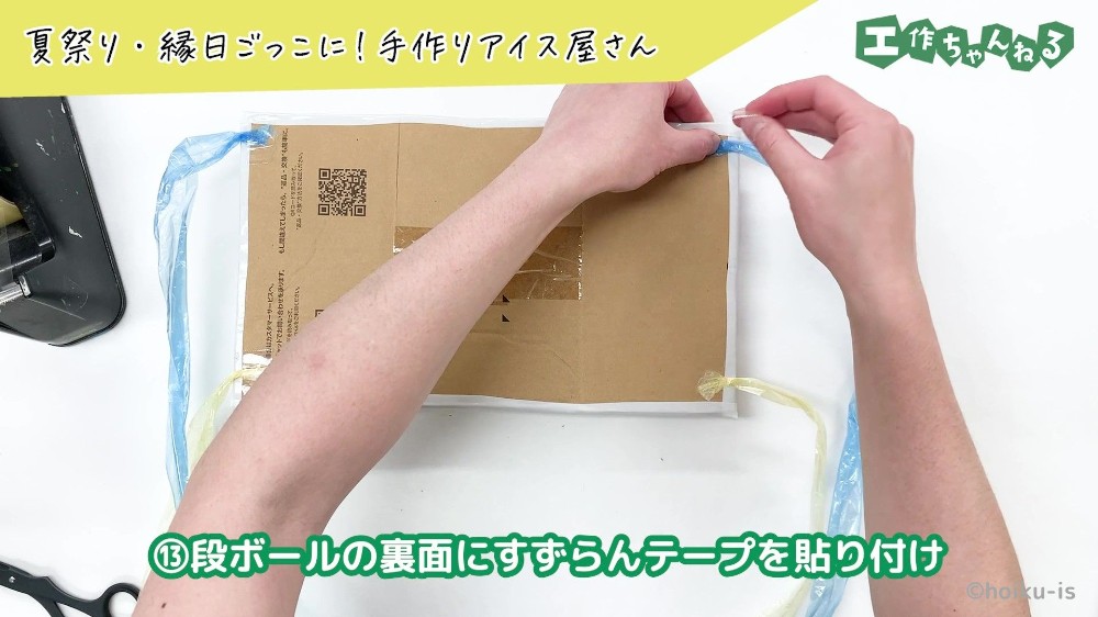 段ボールにすずらんテープを貼り付けている手元
