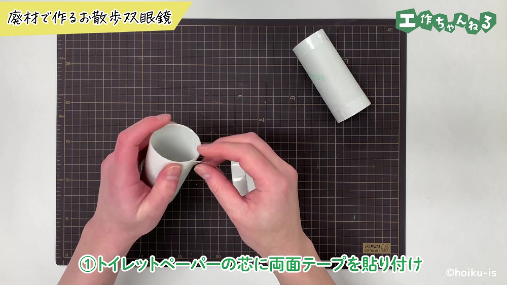 トイレットペーパーの芯に両面テープを貼り付けている手元