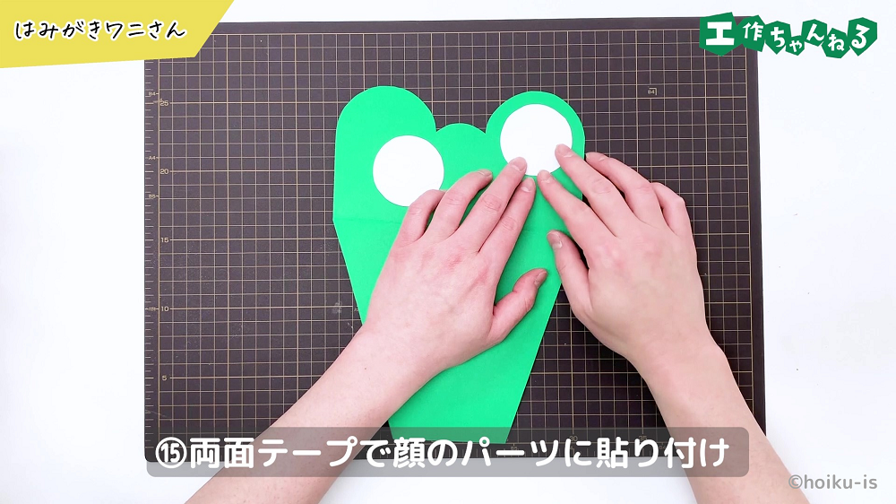 両面テープで丸い画用紙を貼り付けている手元