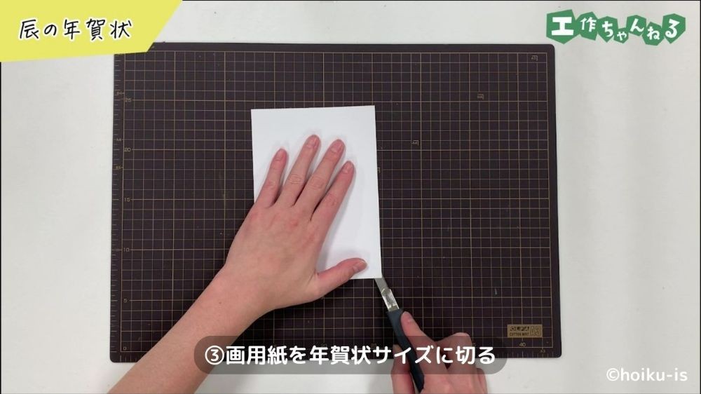 画用紙をカッターで切っている手元