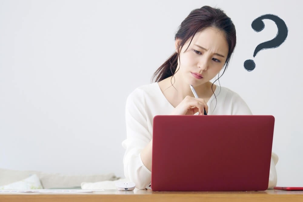 ノートパソコンの前で悩んでいる女性