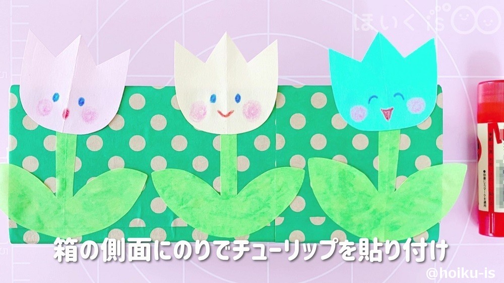 箱の側面にのりでチューリップを貼り付けるところ