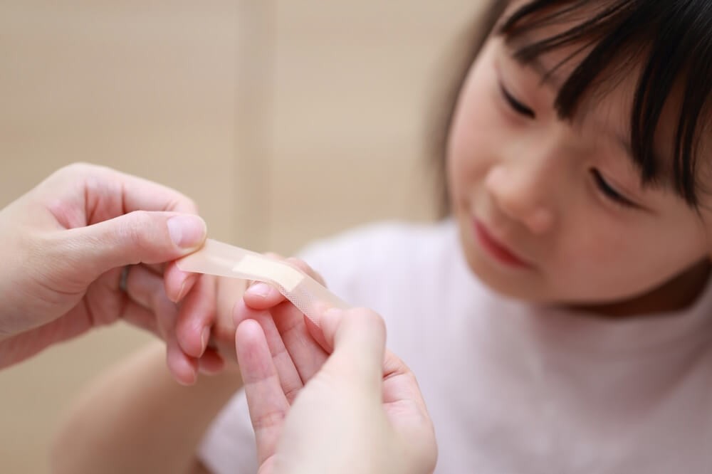怪我をした子どもの指に絆創膏を巻いているところ