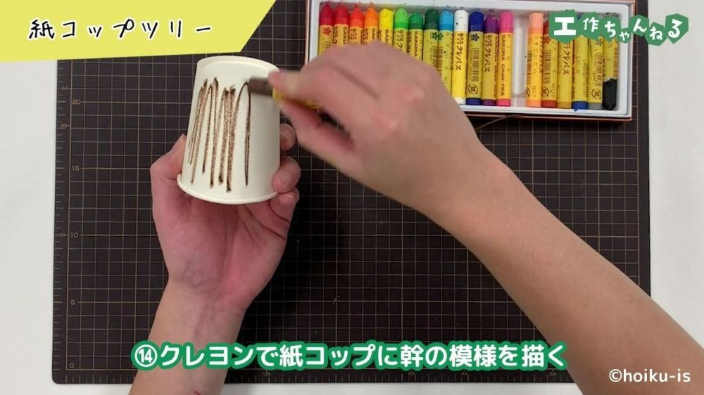 クレヨンで紙コップに色を塗っている手元