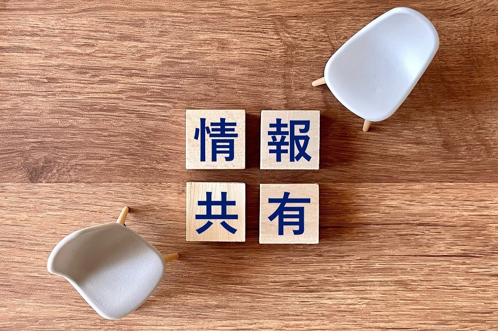 「情報共有」と書かれた積み木と椅子のイメージ