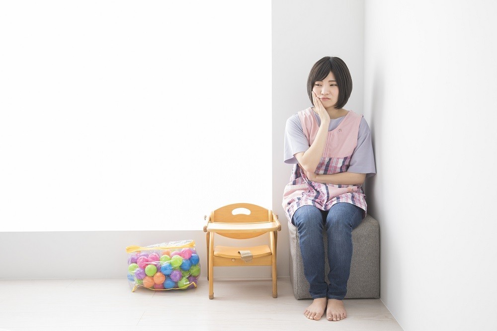 部屋の片隅で悩んでいる保育士