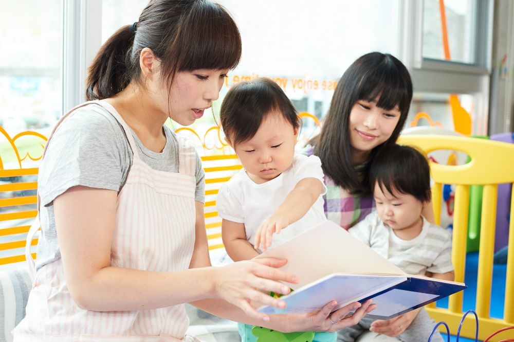 子どもに絵本を読む保育士